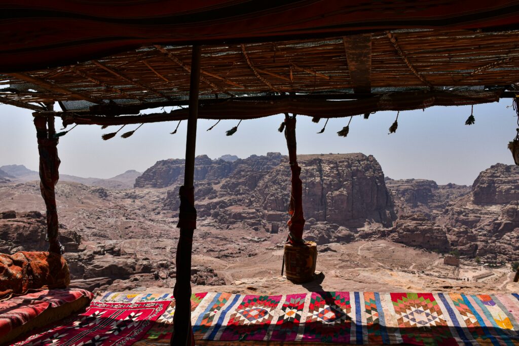 View of the majestic Petra landscape from a shaded shelter with colorful carpets.