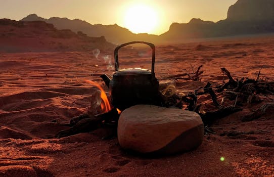 A serene desert sunset with a campfire and kettle in Wadi Rum, Jordan.